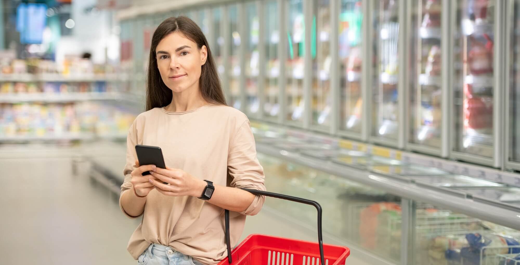 Frau im Supermarkt nutzt App Lebensmittelwarnung.de